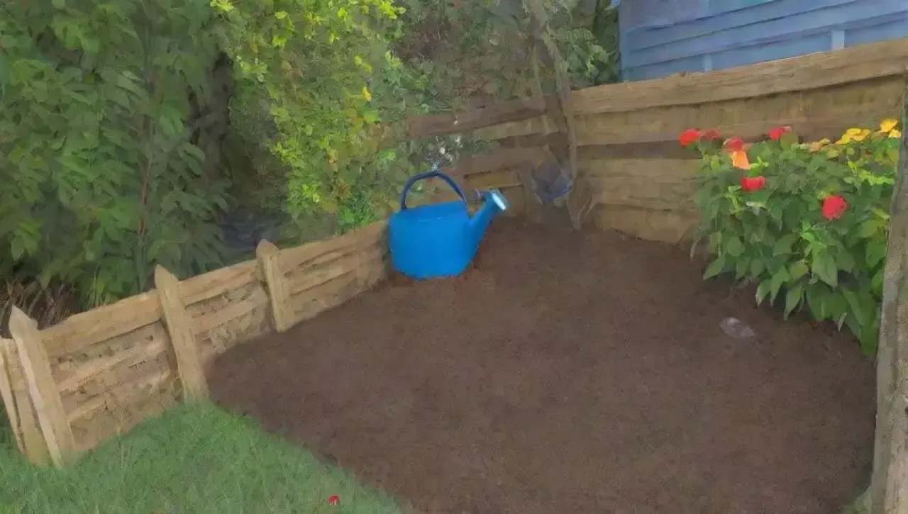 Un vibrante cubo de compostaje verde rodeado de plantas y hojas de otoño bajo un cielo azul