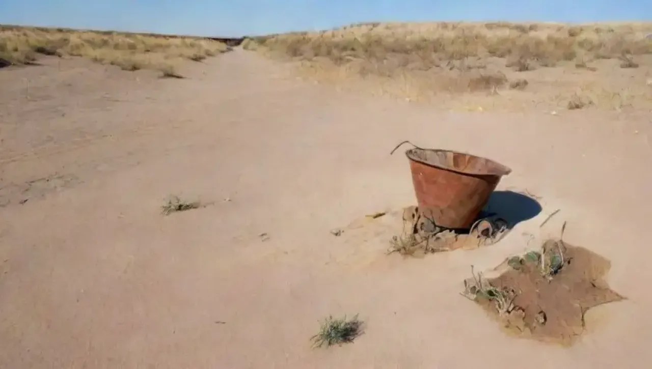 Un paisaje árido y marchito con tierra agrietada, escasa vegetación y signos de erosión